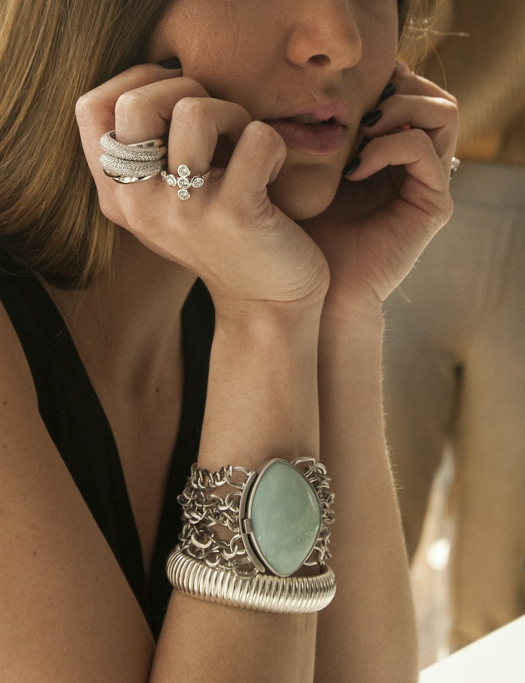  lady with arm adorned with jewelry holds face in hands